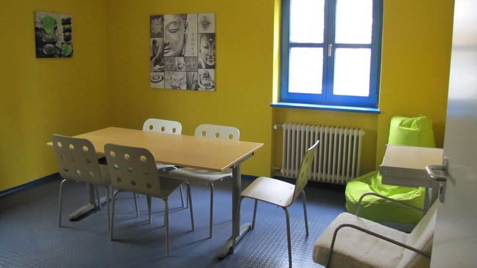 Aufenthaltsraum mit gelben Wänden, Tisch und Stühlen