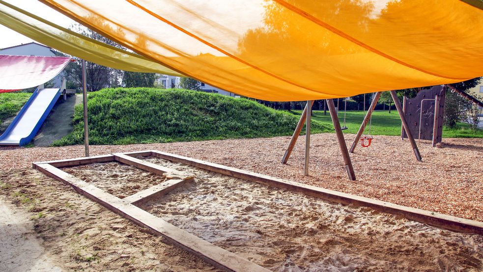 Mehrere Sonnensegel darunter ein Sandkasten und im Hintergrund eine Rutsche