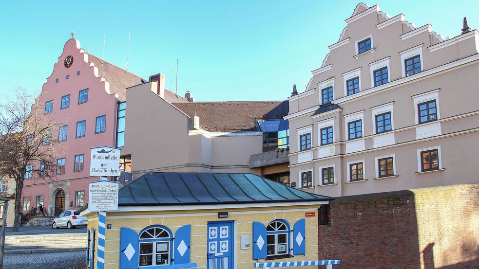 Kleines gelbes Häuschen mit hellblau-weißer Tür und Fensterläden, im Hintergrund weitere Altstadthäuser