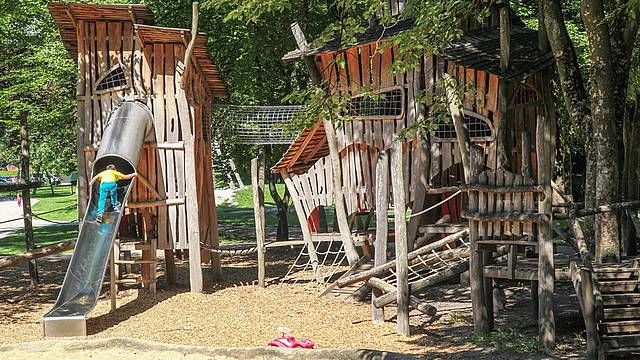 Kind auf Rutsche auf Spielplatz mit vielen Klettermöglichkeiten