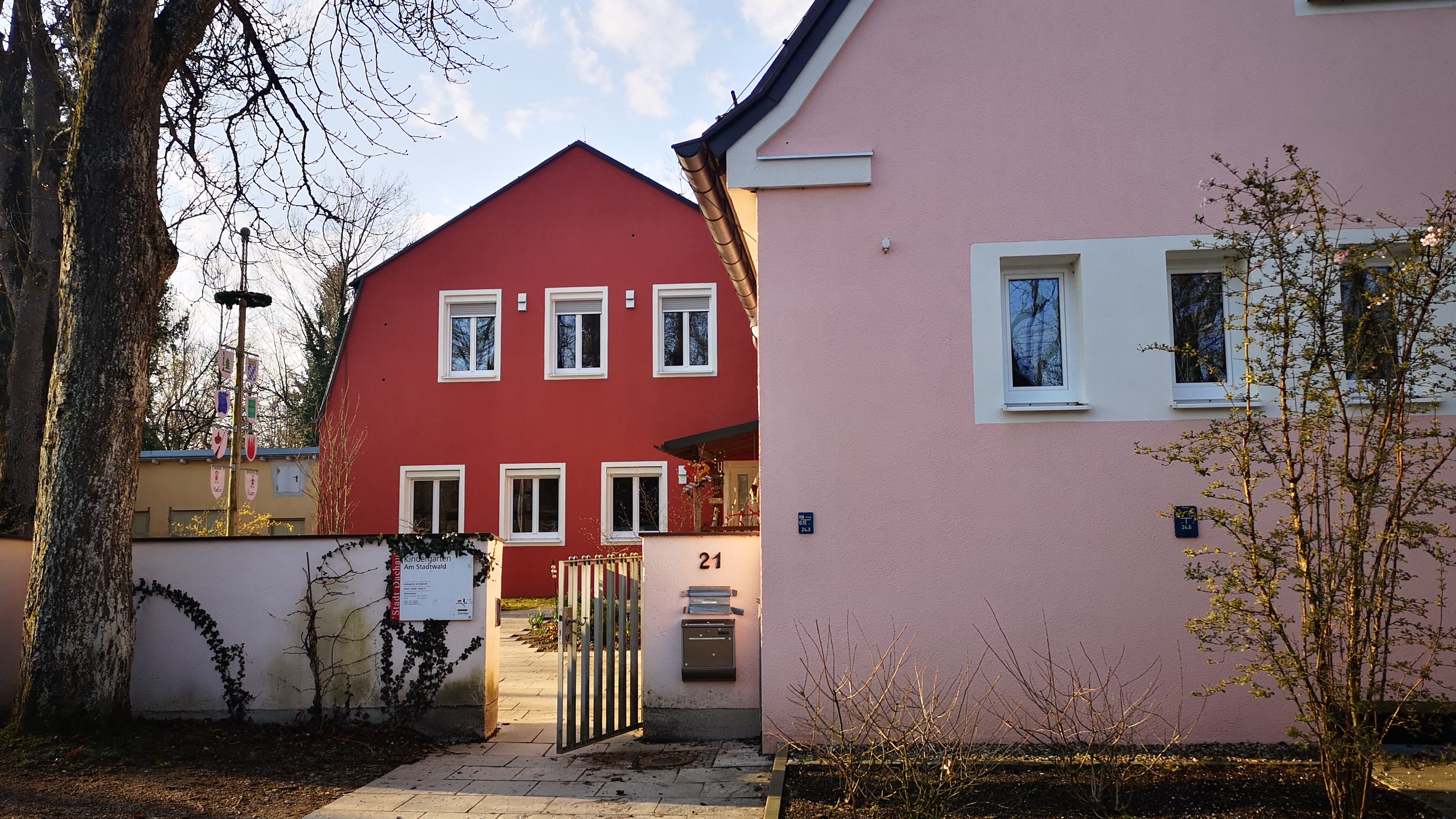 Offenes Gartentor mit rosa und rotem Haus dahinter