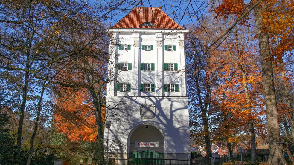 Weißer Turm mit rotem Dach und Bäumen