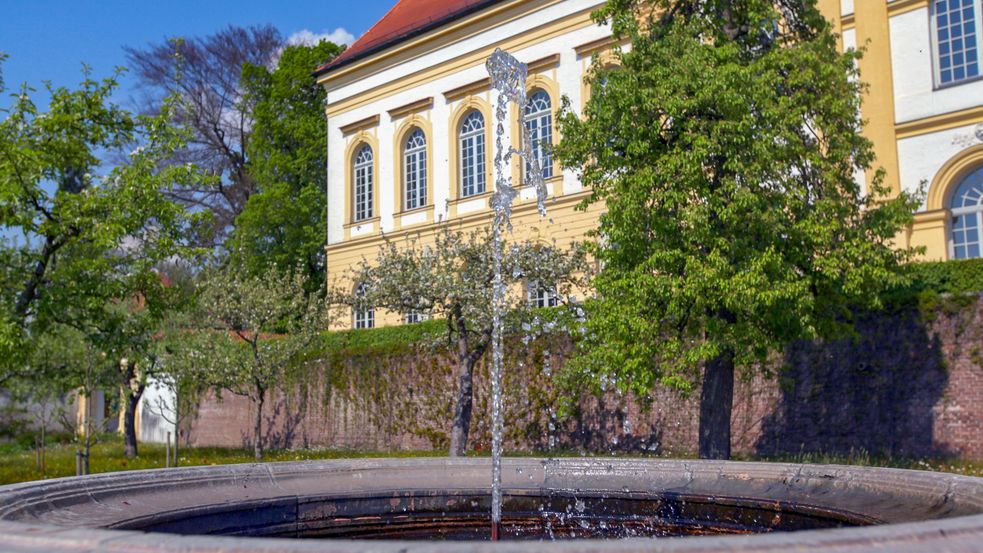 Springbrunnen und Bäume vor dem Schloßgebäude