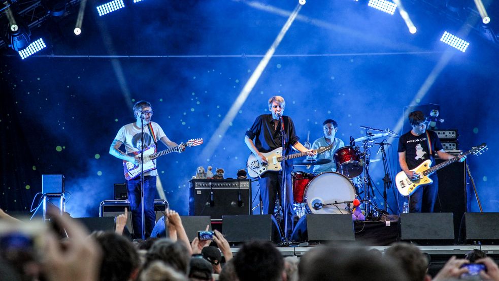 Photo of musicians on stage during Dachau Summer of Music: the photo shows an open-air stage with musicians, bathed in blue light, concert guests in front. Photo: City of Dachau