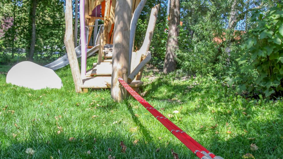 Slackline über Wiese gespannt neben Rutschenhäuschen