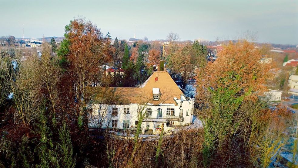 Foto aus Vogelperspektive, auf einem bewaldeten Hügel steht eine Villa