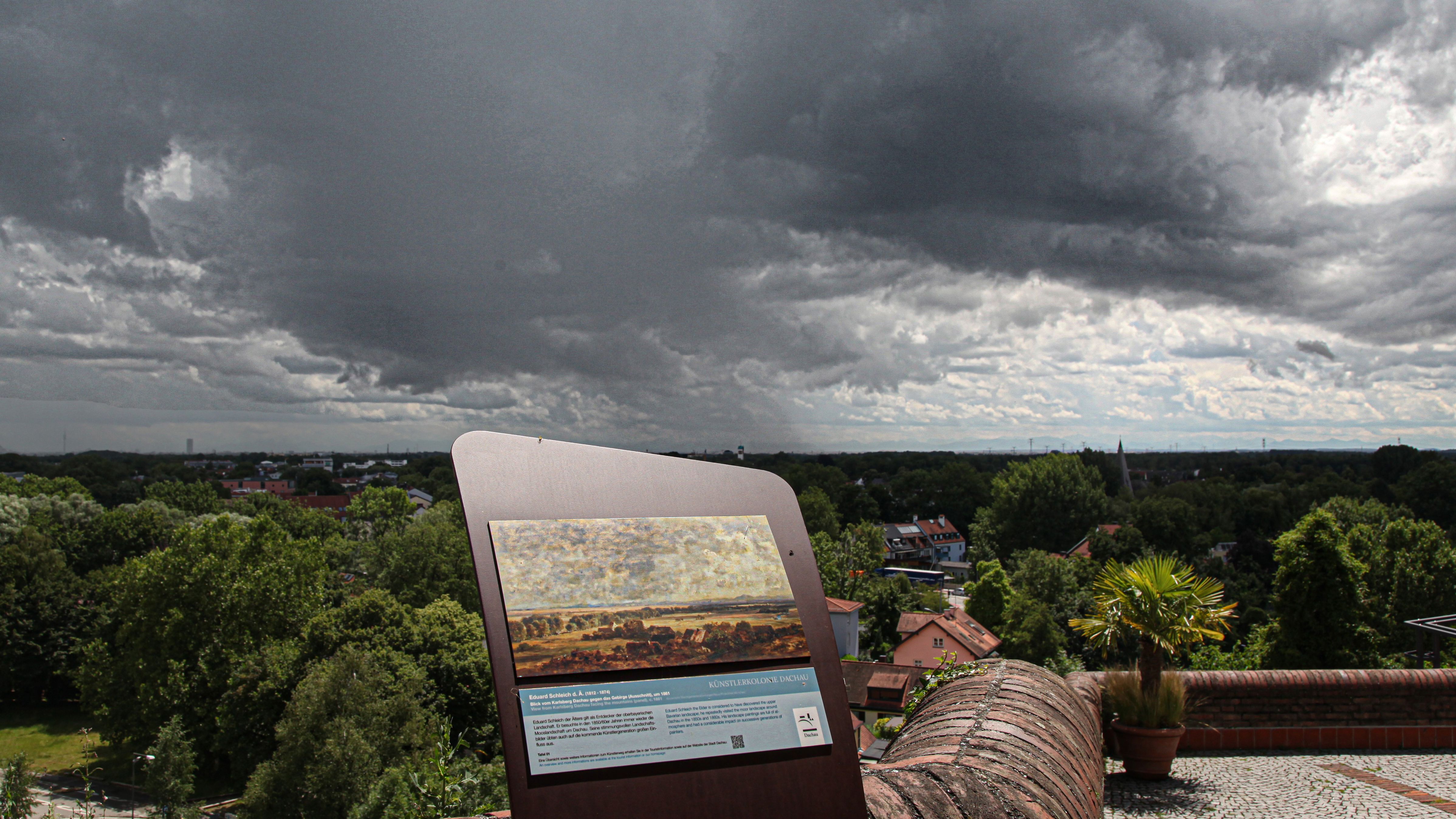 Erste Stele des Künstlerwegs Dachau auf der Rathaus-Terrasse, Blick nach München und zu den Alpen, am Himmel unheilvolles Wolkenbild