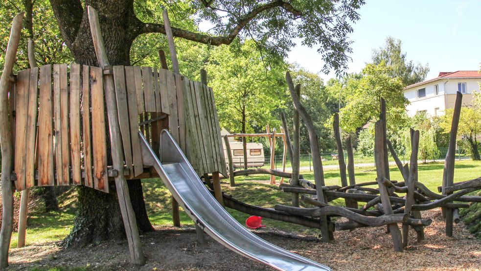 Baumhaus mit Rutsche neben Kletterschlucht und Baum