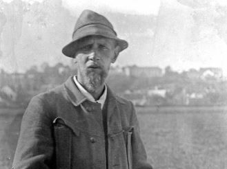 Painter Hans von Hayek, black and white photography of the painter wearing vest and hat standing in a field. Photo: reproduction Zweckverband Dachauer Galerien und Museen
