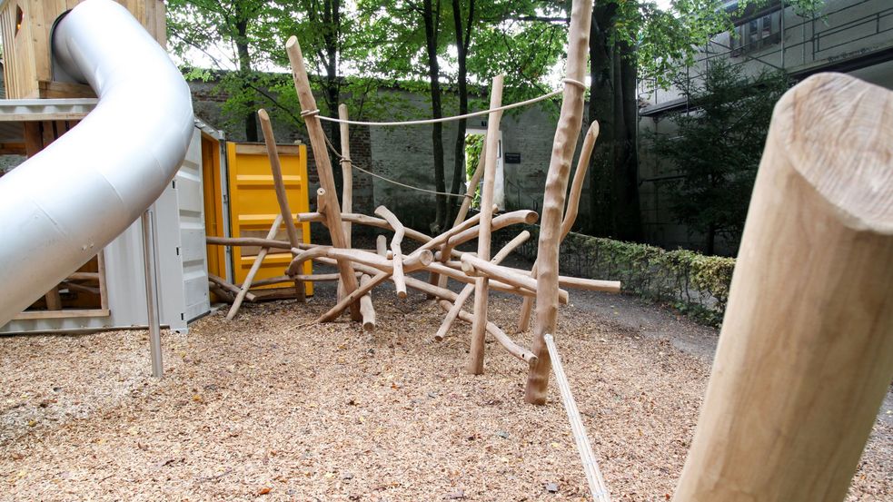 Röhrenrutsche und Kletterstruktur im Sandkasten