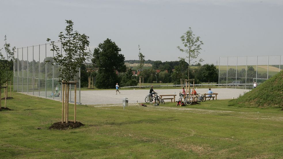 Bolzplatz von weitem mit zwei Toren und Zäunen dahinter