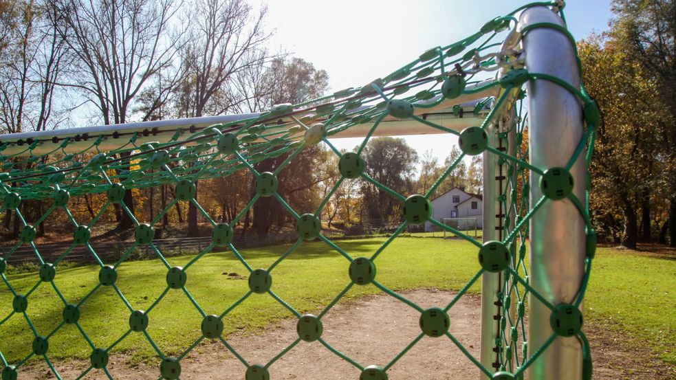 Fußballtor mit grünem Netz, dahinter Bolzplatz