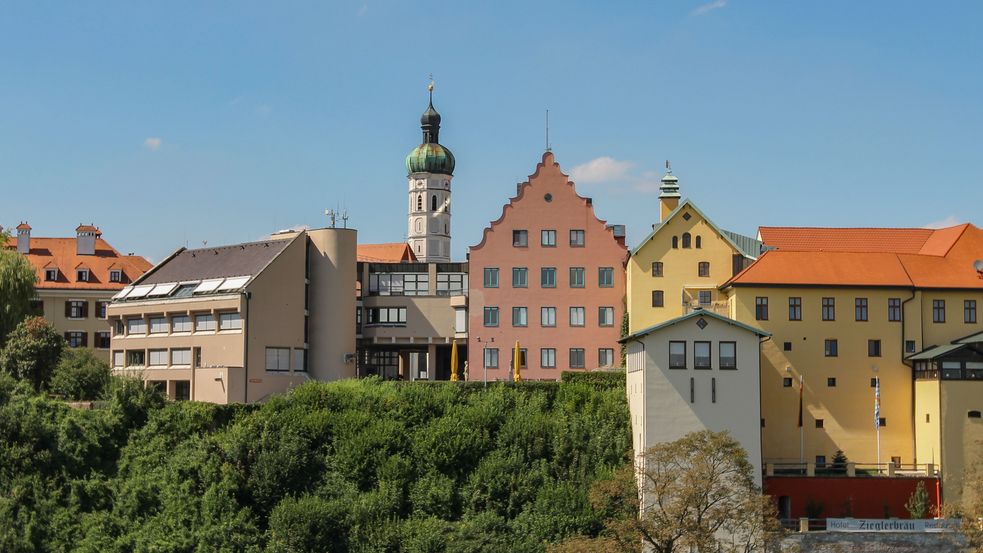 Kirchturm von Häusern und Bäumen umrahmt