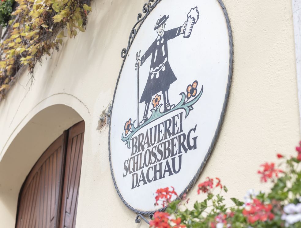 Schild mit Aufschrift Brauerei Schlossberg Dachau und Figur mit Bier in der Hand
