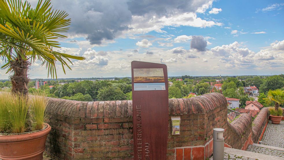 Photo of artist's path stand with replica of painting on town hall terrace with view over Dachau. Partially blue sky with heavy clouds over head. Photo: City of Dachau