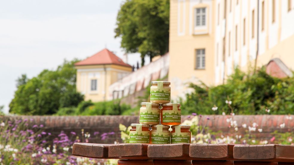 Drei Honiggläser "Dachauer Schloss-Garten-Honig" vor der Schlossmauer
