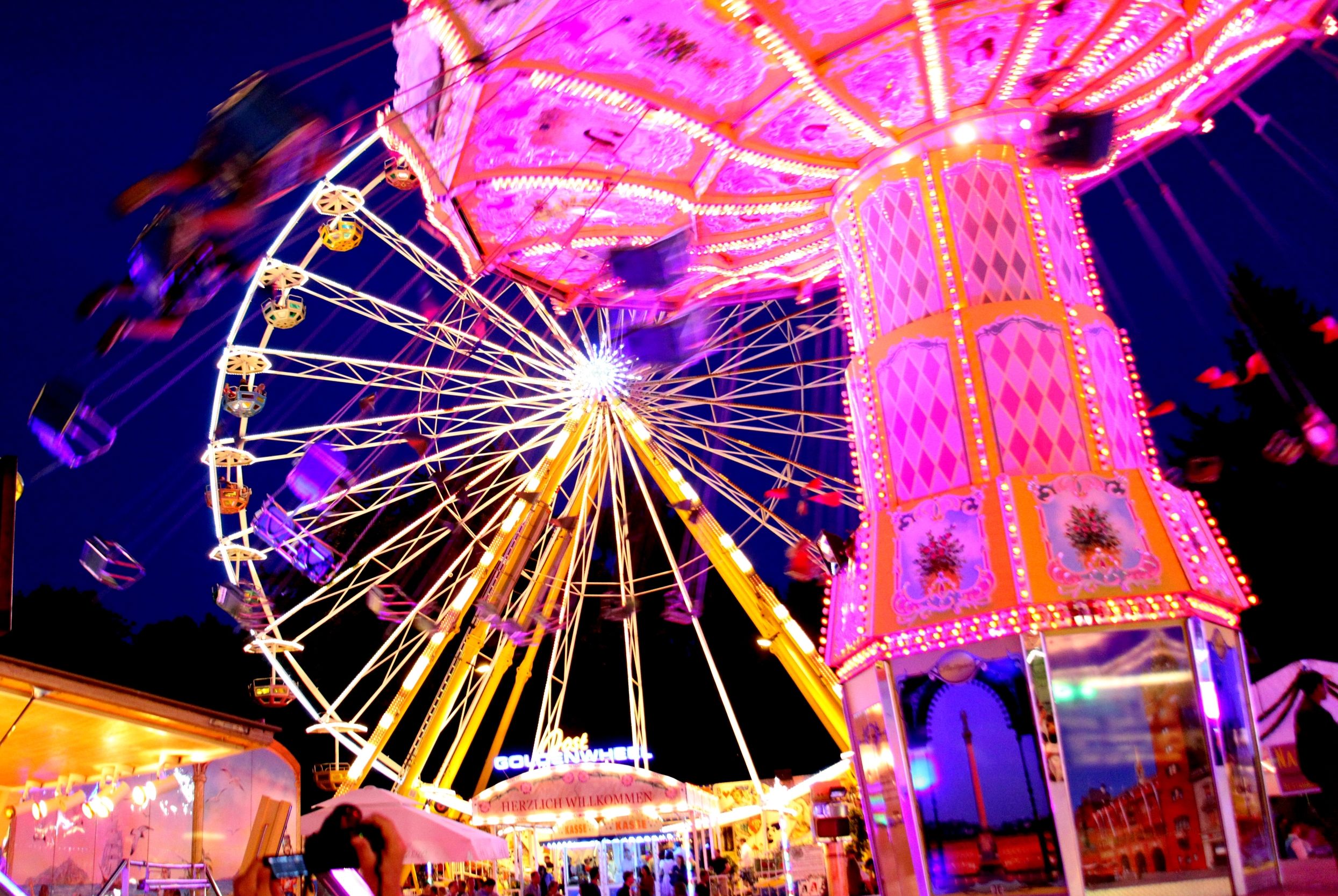 Dachau trational country fair at night, illuminated chain carousel and Ferris wheel against the dark sky. Photo: City of Dachau