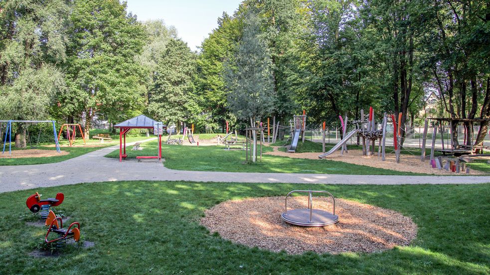 Spielplatz von weitem umgeben von Wiese und Bäumen