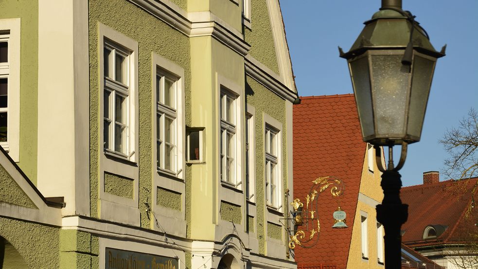 Fot der Fassade des Traditionswirtshauses "zum Kochwirt" in Dachaus Altstadt, grünes Haus mit Zunftzeichen und Straßenlaterne im Vordergrund. Foto: Stadt Dachau_Jörg Lutz