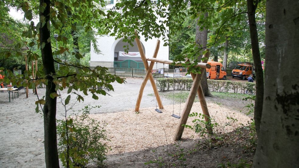 Doppelschaukel im Sandkasten am Rand des Spielplatzes