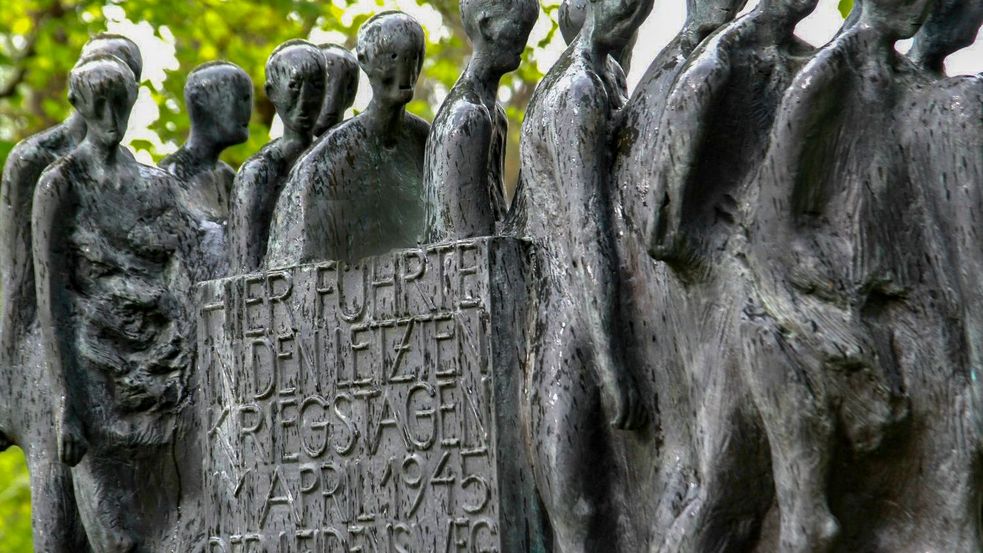 Skulptur zeigt Menschenschlange mit Schildinschrift Hier führte in den letzten Kriegstagen im April 1945...