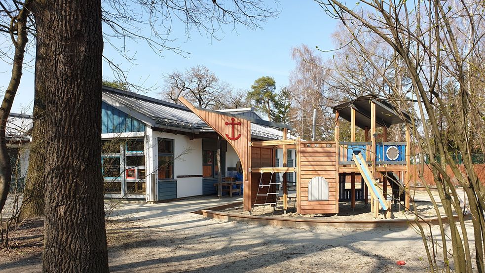 Spielplatz mit Holzturm und Rutsche in Sandkasten