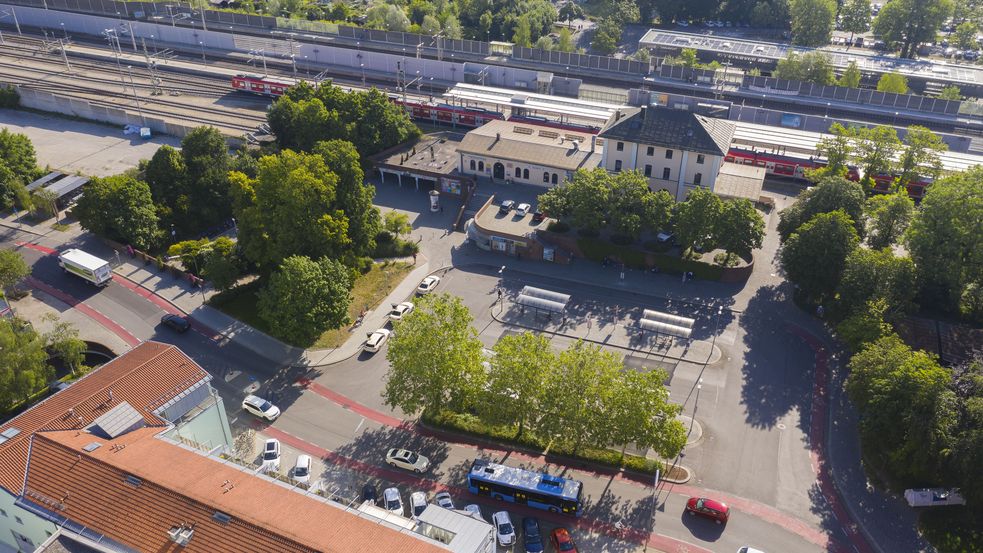 Luftbild von der Westseite des Dachauer S-Bahnhofs mit grünen Bäumen und dem Busbahnhof