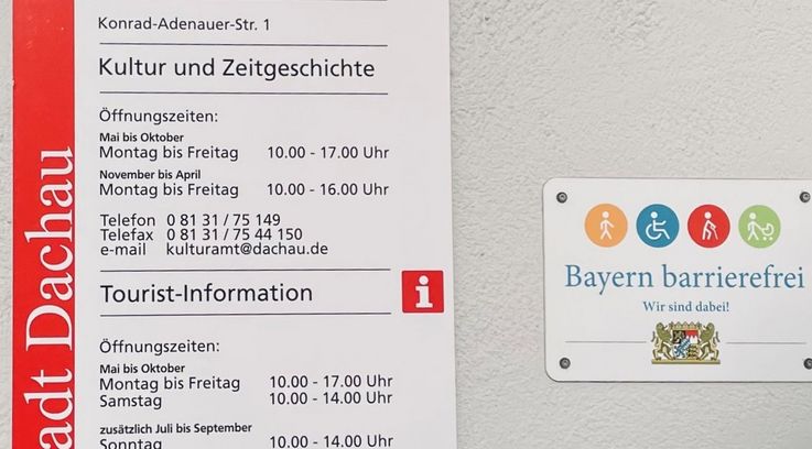 Signs on barrier-free accessibility and opening hours at the tourist information office in Dachau