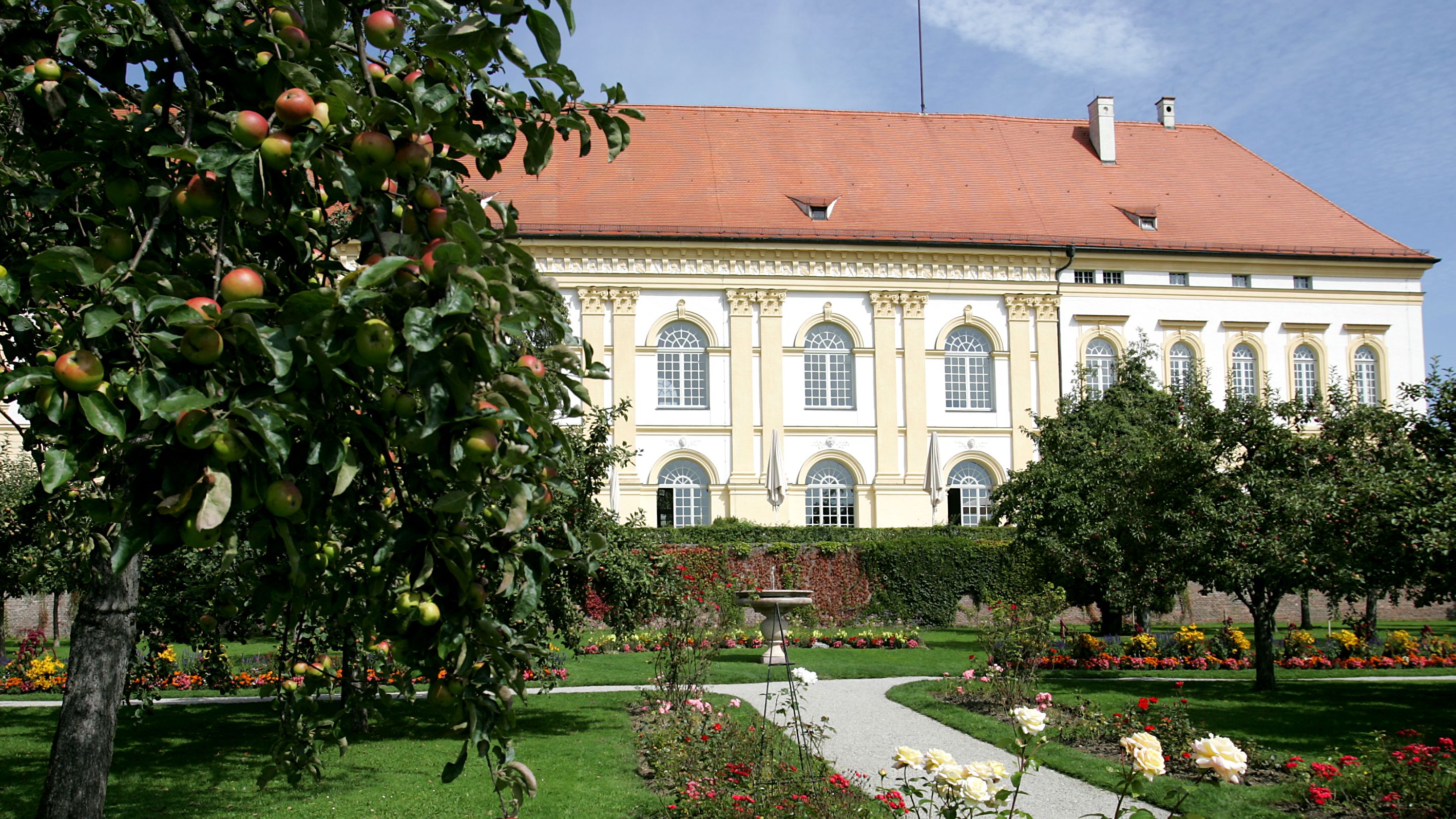 Rosen und Obstbäume im Garten mit Schloss im Hintergrund