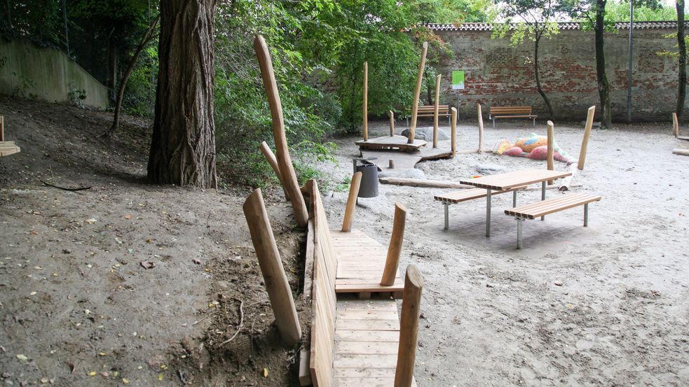 Sitzbankkombinationen am Rande des Sandkastens, Mosaikdrachen im Hintergrund