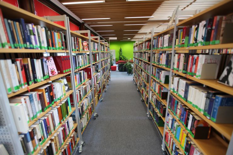 Ein Gang in der Stadtbücherei, links und rechts davon hohe Regale mit Büchern
