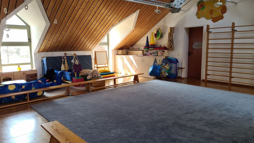 Raum im Dachgeschoss mit Sprossenwand, Gymnastikmatten, Sitzbänken und Teppich