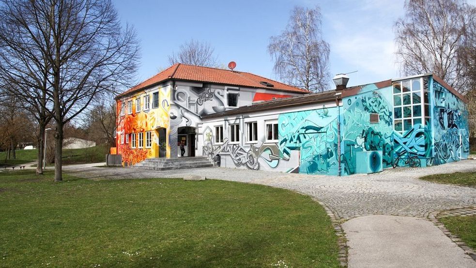 Bunt besprayte Außenfassade des Jugendzentrum Ost Haus mit Wiese davor