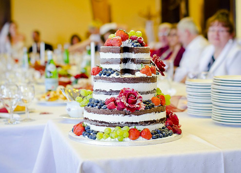 Bunte, dreistöckige Hochzeitstorte, dahinter Hochzeitsgesellschaft