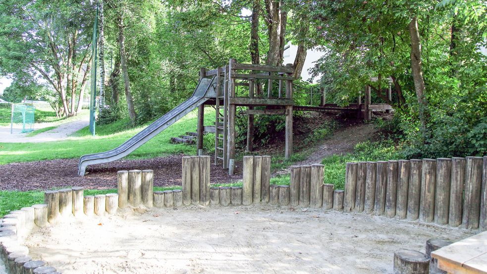 Sandkasten mit Rutsche und Bäumen