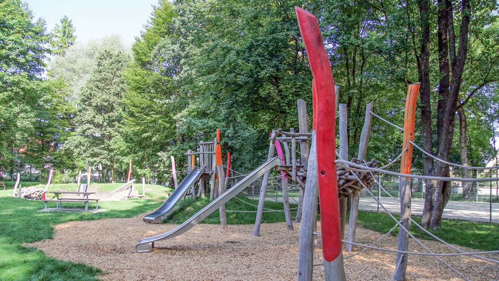 Rutschen im Sandkasten umgeben von Bäumen