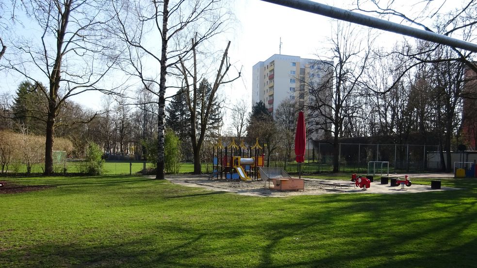 Kleiner Spielplatz mit verschiedenen Spielgeräten auf Sand