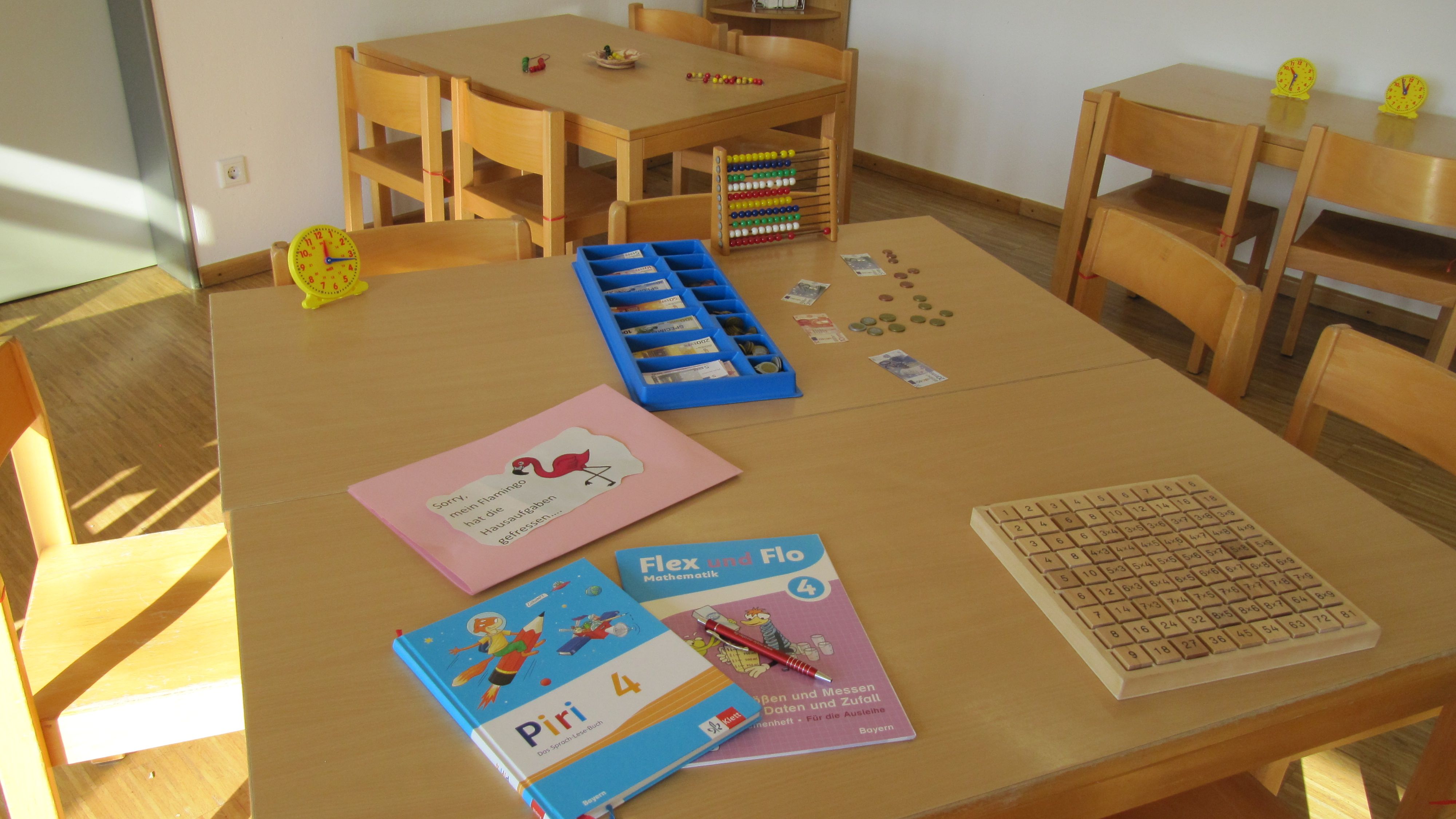 Tisch mit Lernbüchern und Lernhilfsmitteln in Raum mit weiteren Tischen und Stühlen