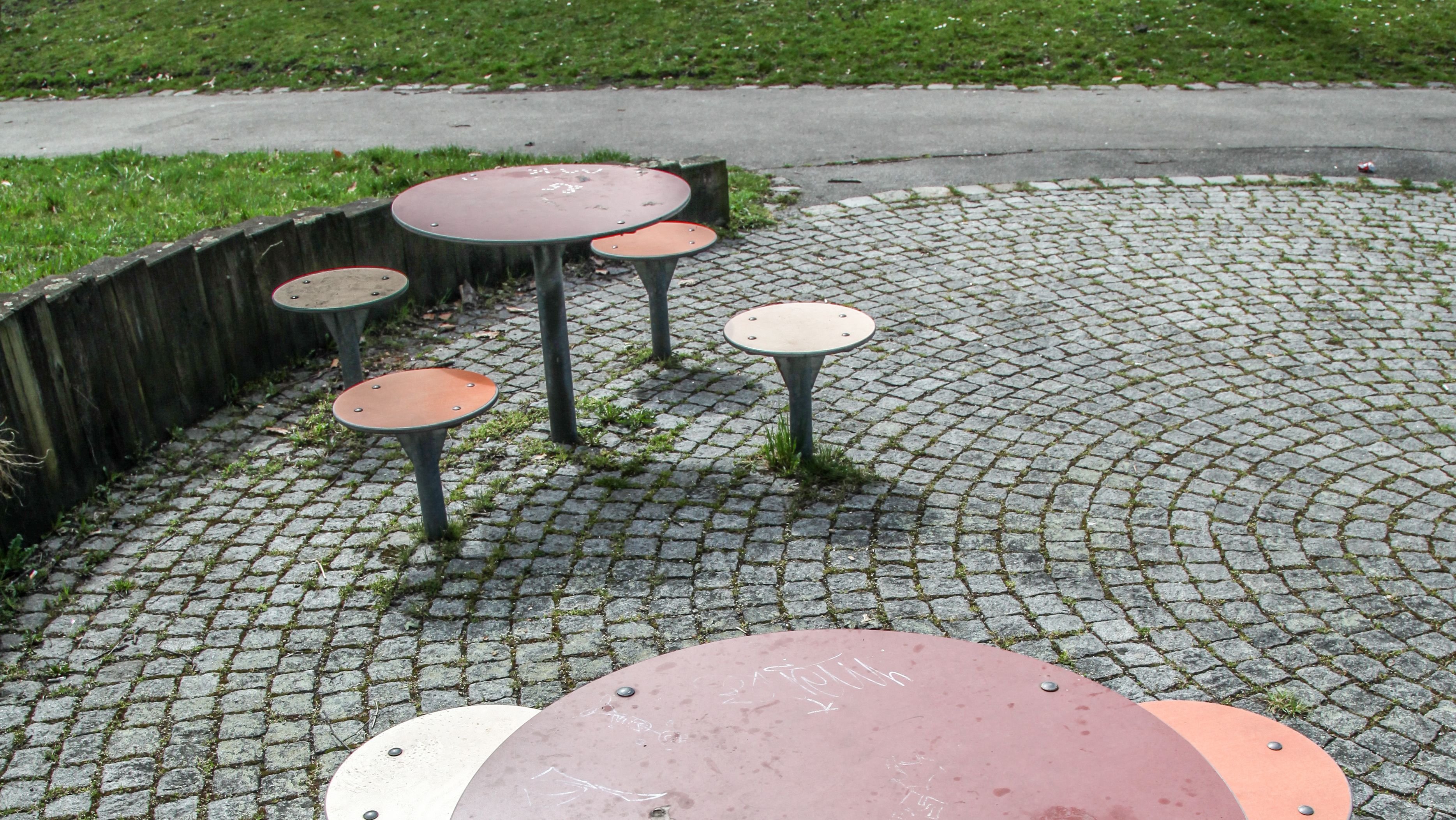 Tische mit Sitzplätzen auf Kopfsteinplaster neben Wiese