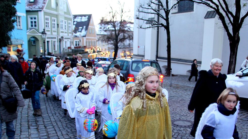 Viele Kinder in weißen Engelskostümen und eins läuft vorneweg mit goldenem Kostüm