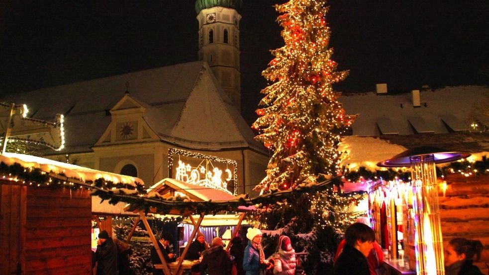 Besucher im Dunkeln inmitten beleuchteter Weihnachtsstände