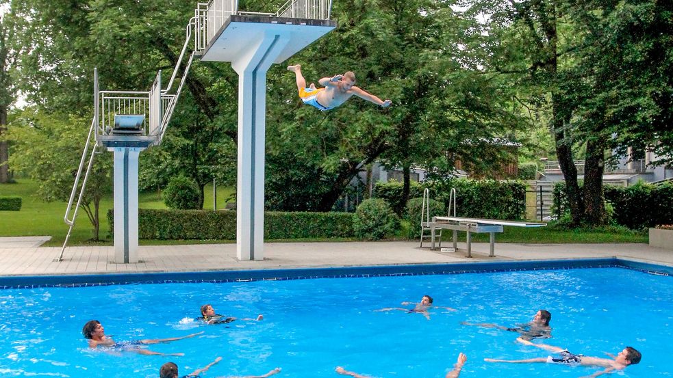 Person spingt vom 5 Meter Brett ins Schwimmbecken