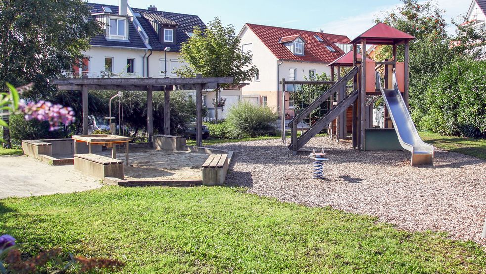 Sandkasten mit Rutsche und vielen Sitzgelegenheiten daneben