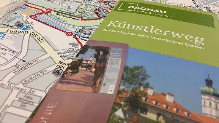 Titel des Flyers zum Künstlerweg Dachau liegt auf einem zweiten Flyer zum Künstlerweg, der aufgeklappt ist