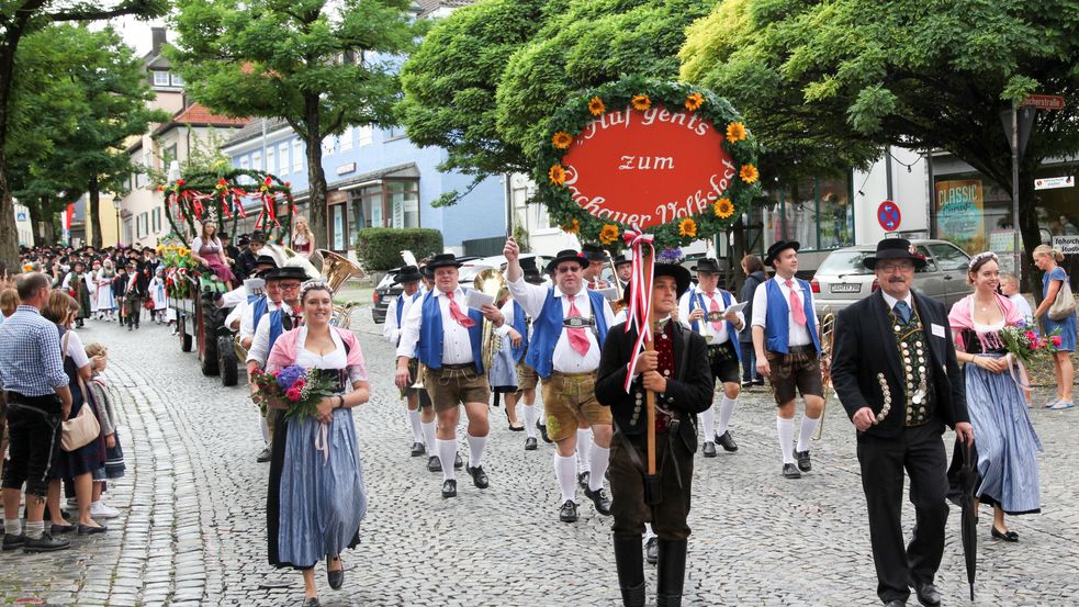Photo of people in traditional garb walking in opening parade at Dachau country fair (Dachauer Volksfest), carrying signs. Photo: City of Dachau