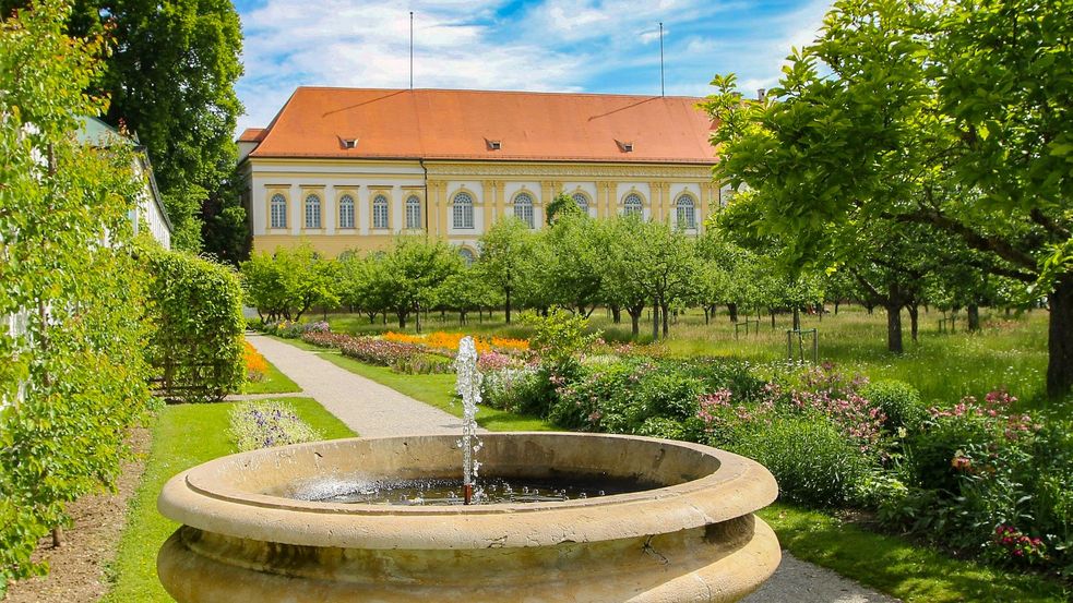 Steinbrunnen vor dem Schloß mit Bäumen im Park