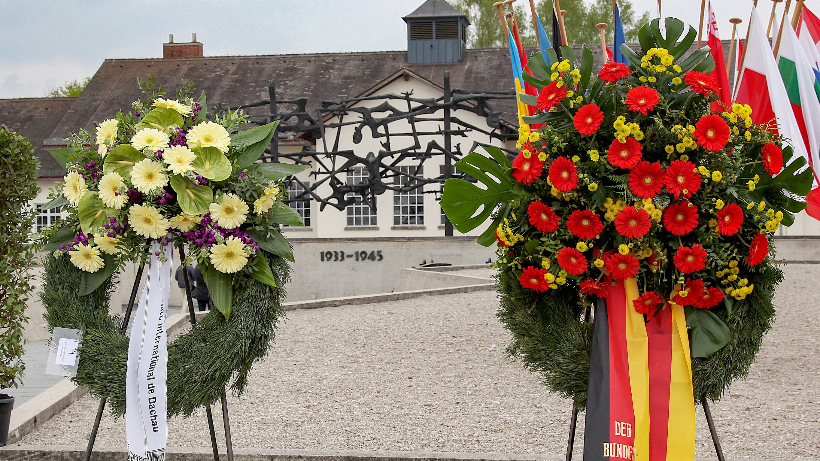 Photo of flower wreaths at Concentration Camp Memorial Site Dachau with International Memorial and "jouhaus" in the background. Photo: City of Dachau