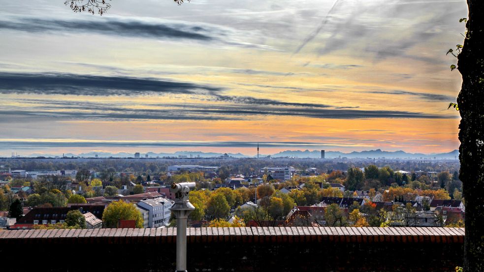 Photo of view from Dachau Palace during "Föhn" wind (warm wind from the South). Telescope in front of the palace wall and a tree on the right. Dachau down below and dramatically coloured sky. Photo: City of Dachau