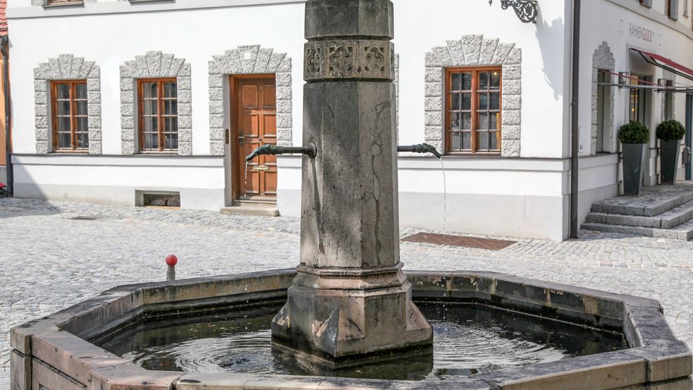 Steinbrunnen vor einem weißen Altstadthaus