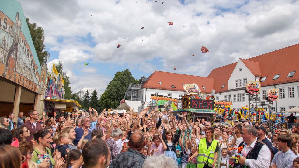 Menschenmenge auf einem Platz, es fliegen Bonbons durch die Luft